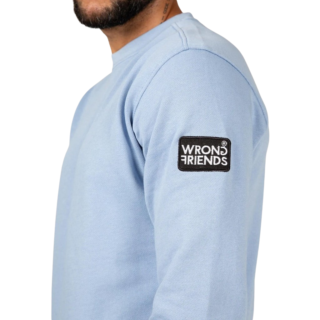 Model wearing the light blue Wrong Friends Leon crewneck, with branded sleeve patch.