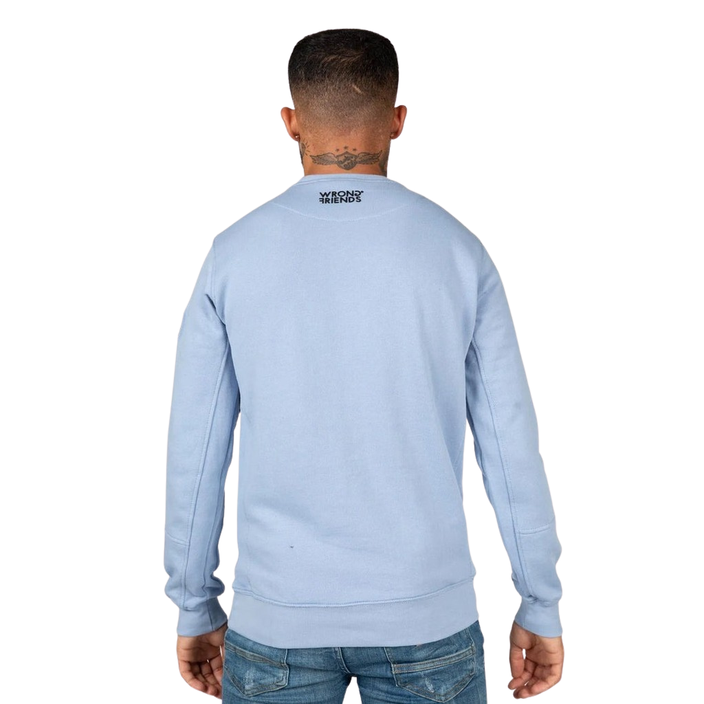 Model wearing the light blue Wrong Friends Leon crewneck, with branded sleeve patch.