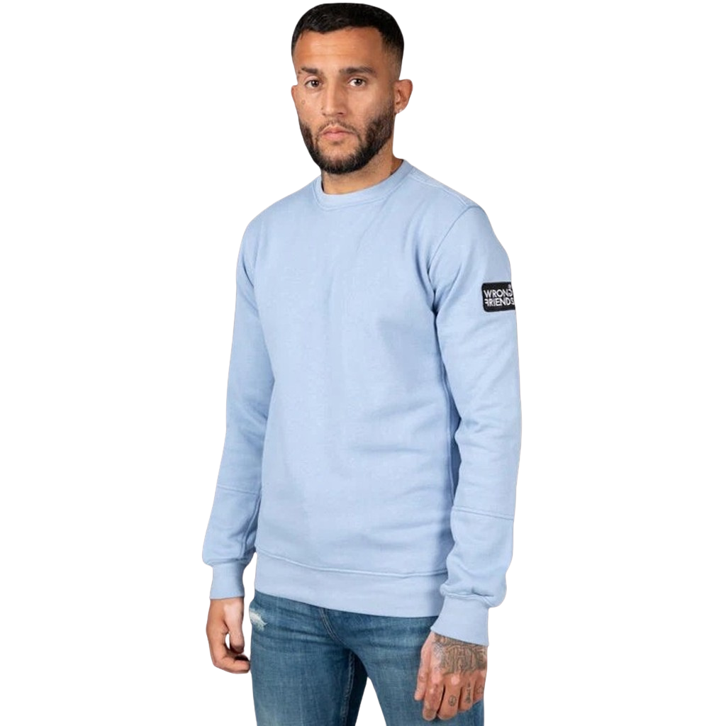 Model wearing the light blue Wrong Friends Leon crewneck, with branded sleeve patch.