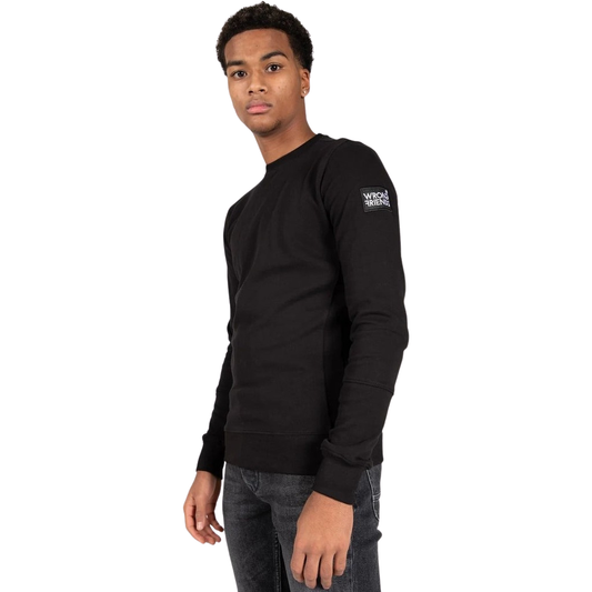 Model wearing the black Wrong Friends Leon crewneck, with branded sleeve patch.