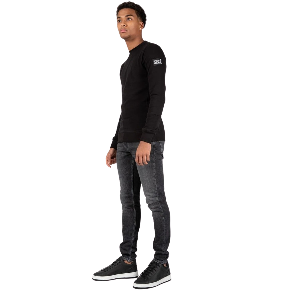 Model wearing the black Wrong Friends Leon crewneck, with branded sleeve patch.