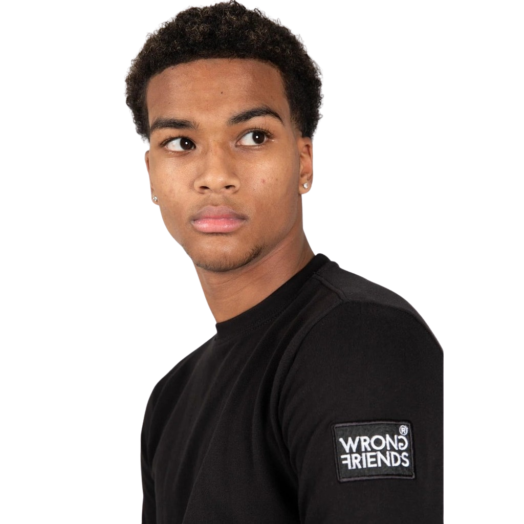 Model wearing the black Wrong Friends Leon crewneck, with branded sleeve patch.