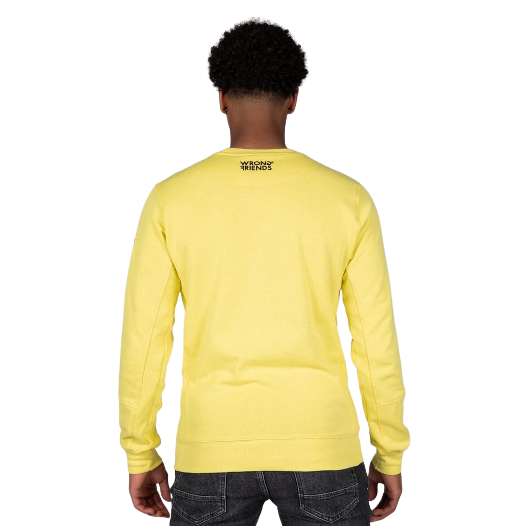 Model wearing the yellow Wrong Friends Leon crewneck, with the branded sleeve patch
