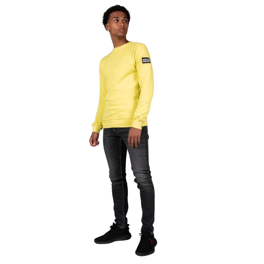 Model wearing the yellow Wrong Friends Leon crewneck, with the branded sleeve patch