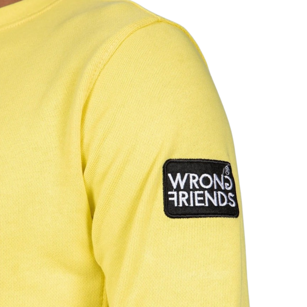 Model wearing the yellow Wrong Friends Leon crewneck, with the branded sleeve patch